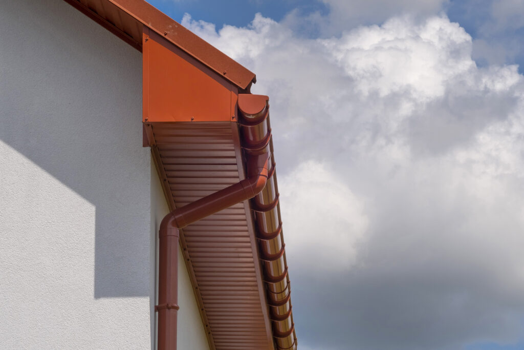 A metal roof of the house and a drain. Close-up side view.